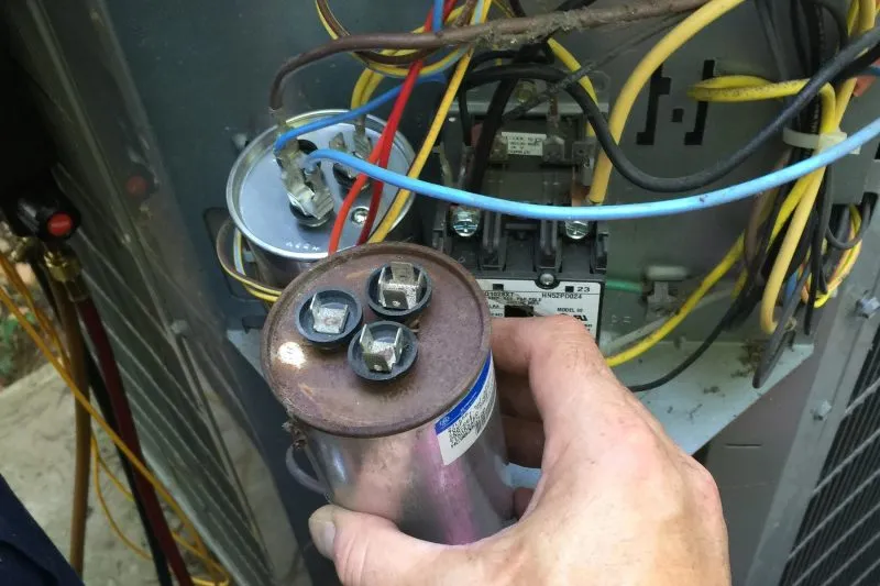 A technician replacing a capacitor on a circuit board.