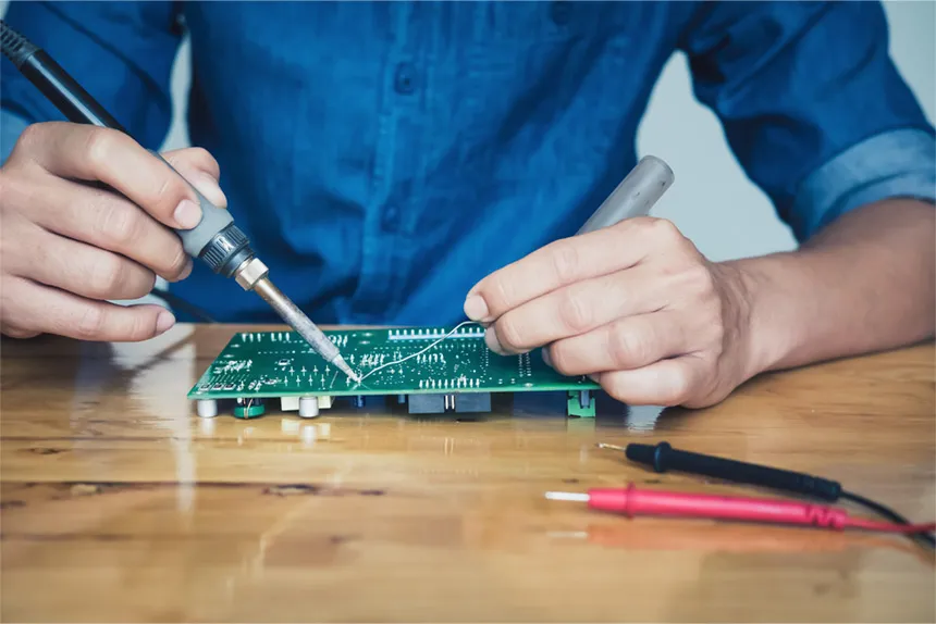 A person hand-soldering components onto a PCB.