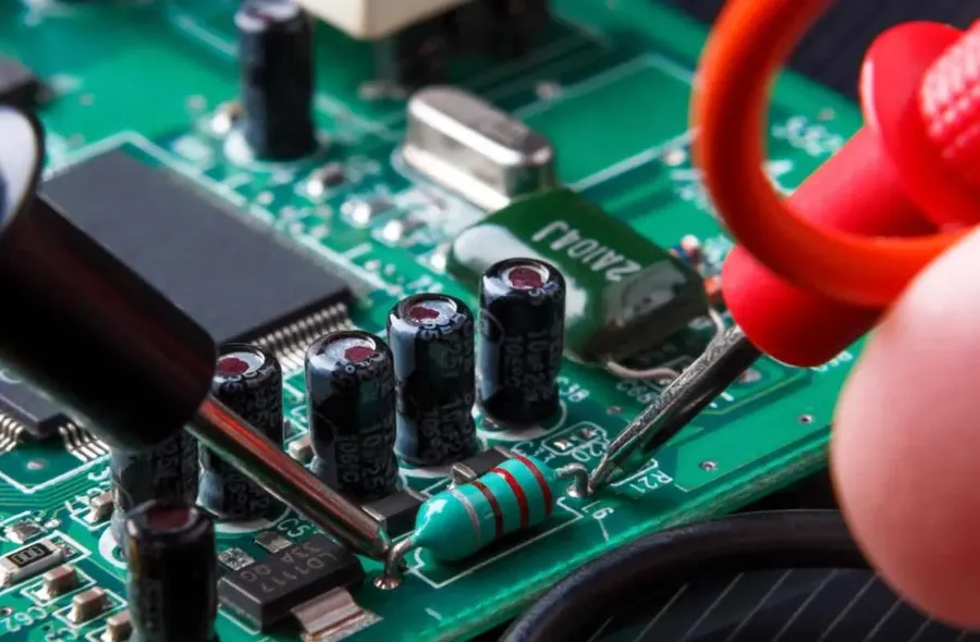 Hands repairing a PCB board with tools.