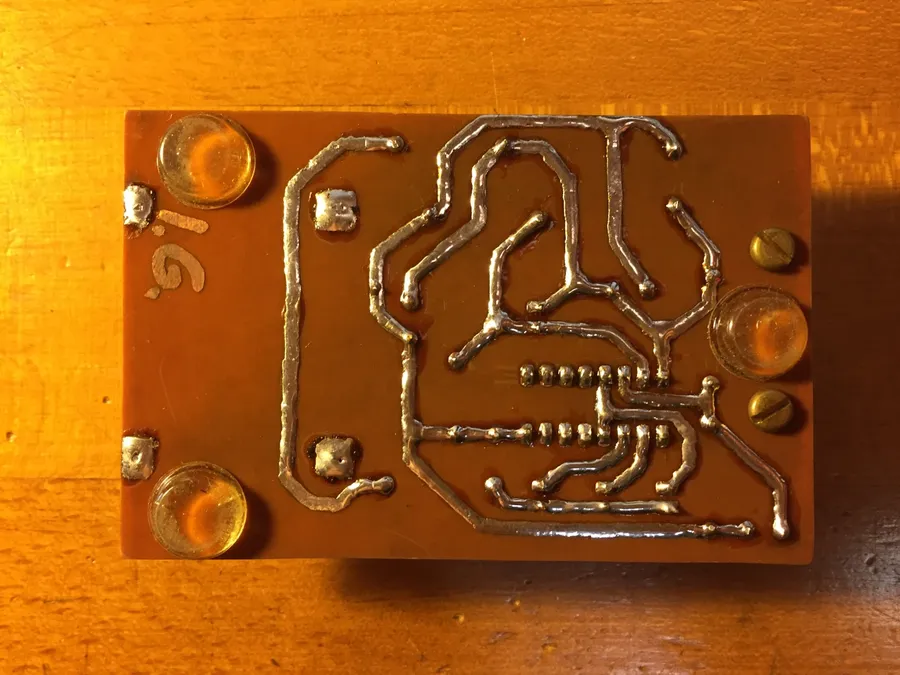 A close-up of a DIY etched PCB using chemicals and a laser printer toner transfer method.
