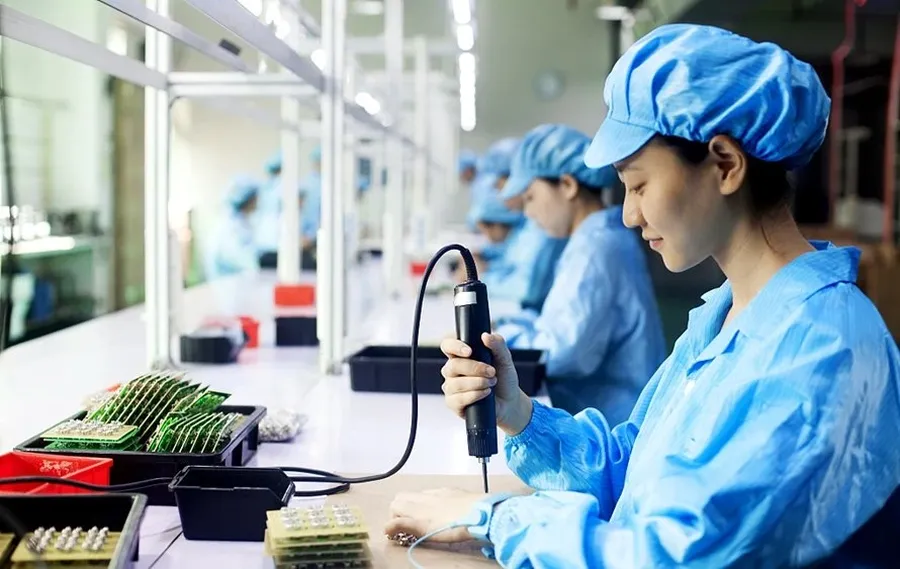 Workers assembling PCBs on a production line.
