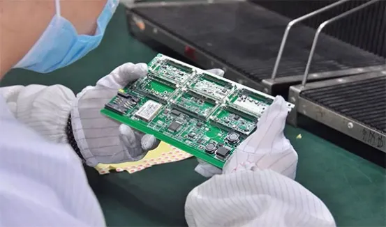 A close-up of a PCB being inspected with magnifying glass or other tools.