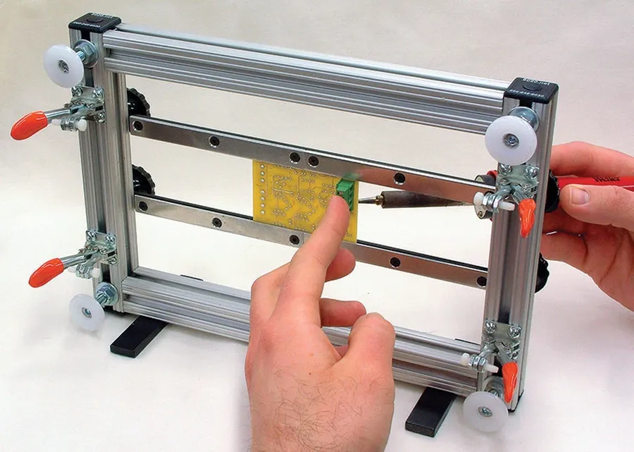 A person working on assembling a PCB at a workbench.
