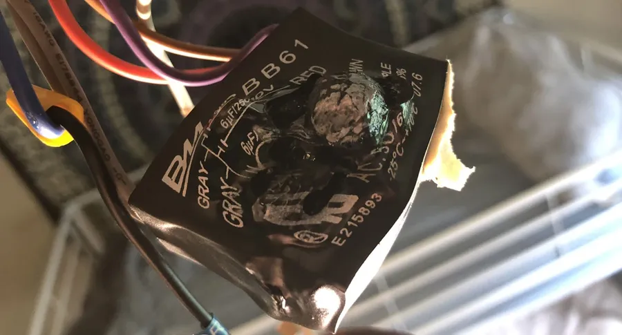 A swollen or leaking fan capacitor, indicating failure.