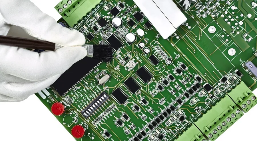 A person cleaning the PCB of an air conditioner with a brush