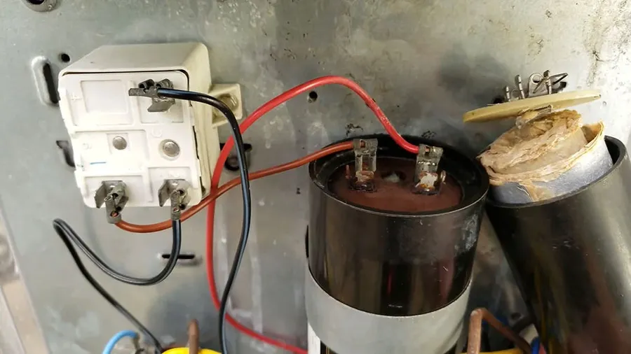 A visibly damaged start capacitor, showing signs of failure.