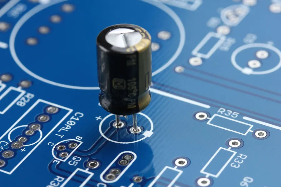 An electrolytic 1uF capacitor mounted on a circuit board.