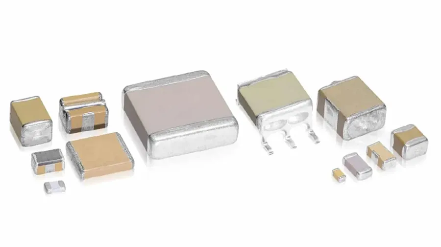 A hand selecting a capacitor from a collection of components.