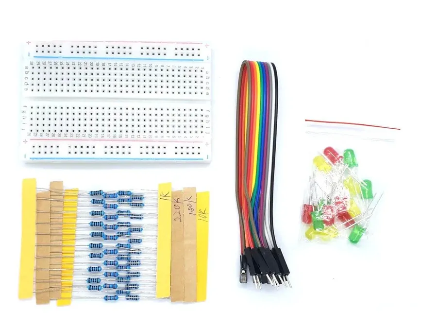 A collection of electronic components including jumper wires, resistors, and an LED arranged near a breadboard.