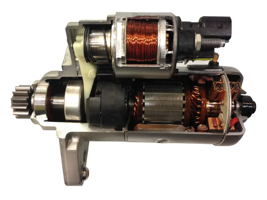 A picture of a car starter motor, showing its solenoid and gear.