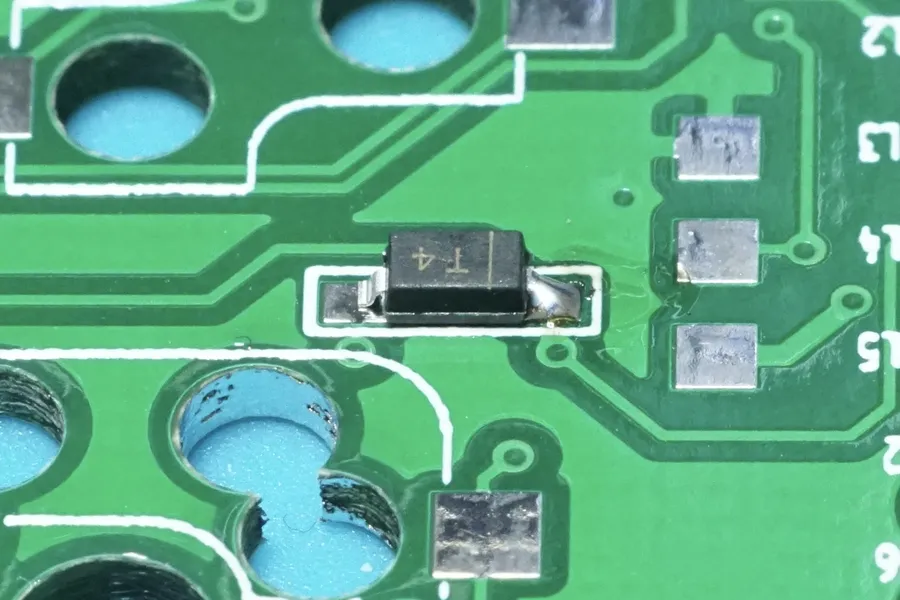 A hand soldering a diode on a PCB.