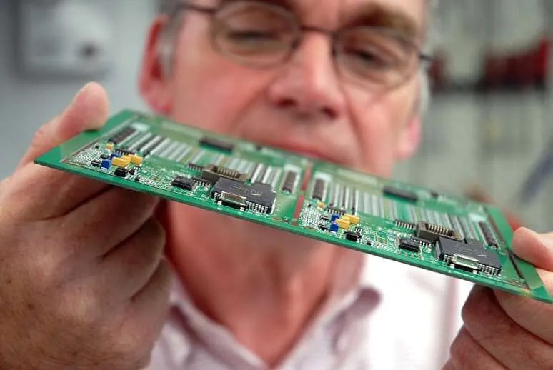 An inspector examining a PCB board with testing equipment.