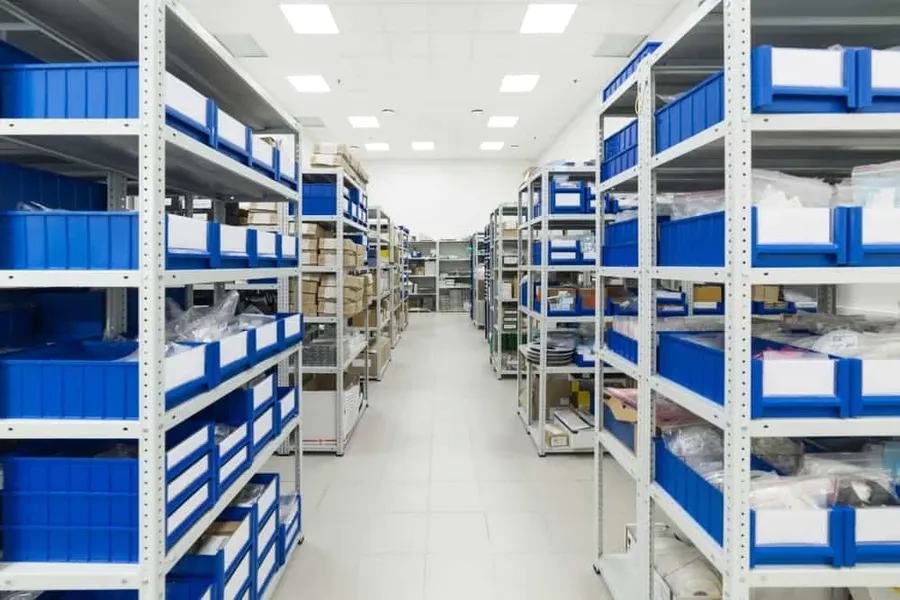 A warehouse worker using a tablet to manage electronic parts inventory.