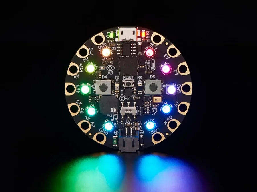 An Adafruit Circuit Playground board with various components and LEDs visible.