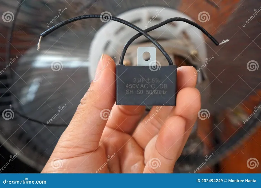 A hand wearing gloves carefully holding a capacitor.