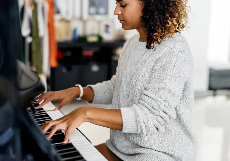 A music student practicing piano in a modern practice room