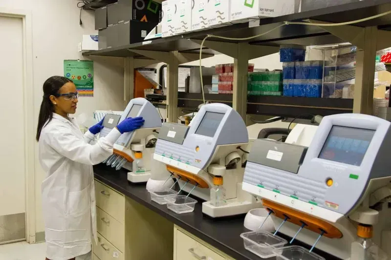 Technician inspecting medical device PCB for quality