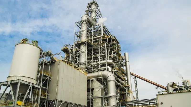 An exterior view of a biomass power generation facility with smoke stacks.