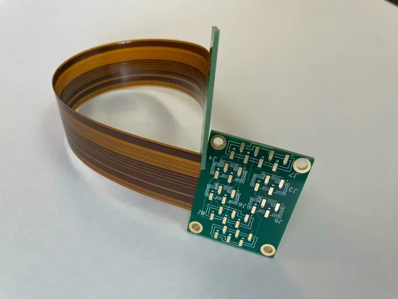 A close-up of a flexible or rigid-flex PCB being bent or shown with its various layers.