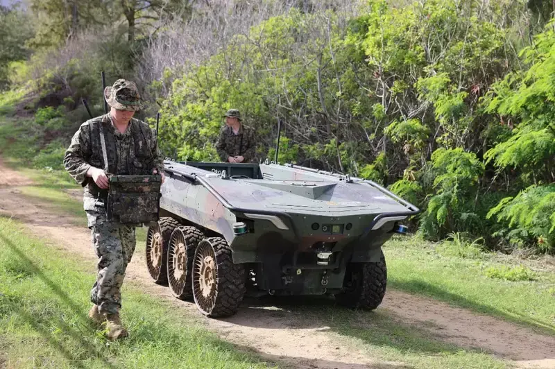 A military unmanned transport vehicle operating outdoors.