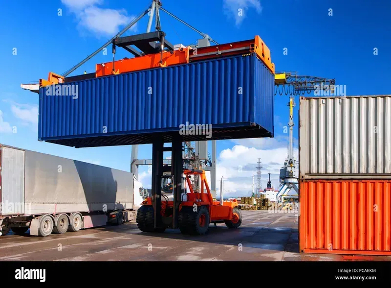 A large port crane lifting and moving a shipping container at a busy port